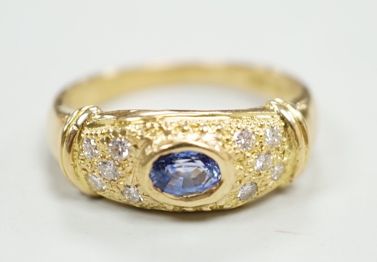 A modern 18ct gold, single stone oval cut sapphire and ten stone diamond chip set ring, size N/O, gross weight, 5.3 grams.